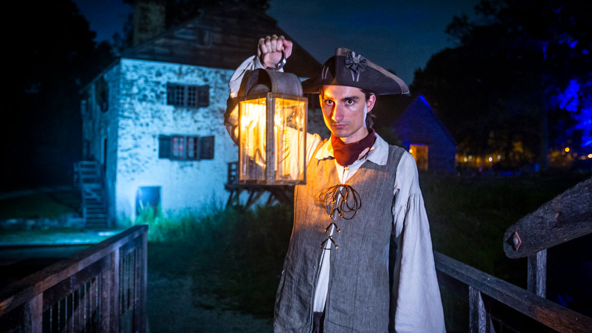 Man in colonial dress holding lantern